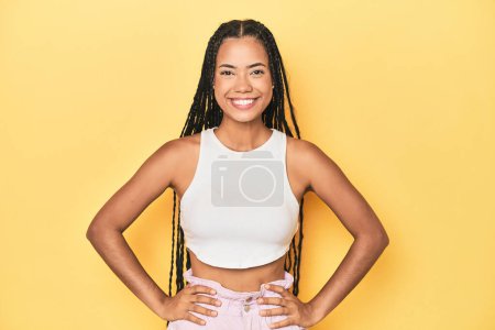 Photo for Young Indonesian woman on yellow studio backdrop confident keeping hands on hips. - Royalty Free Image
