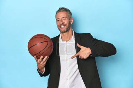 Photo for Middle-aged basketball coach on blue backdrop Middle-aged basketball coach on blue backdropperson pointing by hand to a shirt copy space, proud and confident - Royalty Free Image
