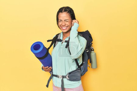 Photo for Indonesian woman ready for mountain trip on yellow covering ears with hands. - Royalty Free Image