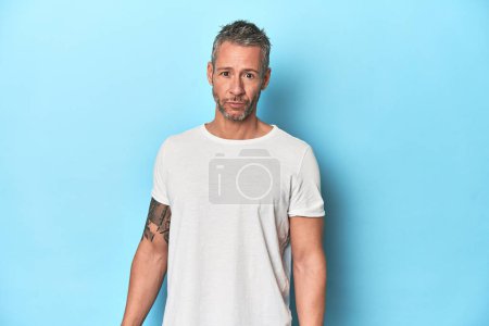 Photo for Middle-aged man posing on blue studio backdrop - Royalty Free Image