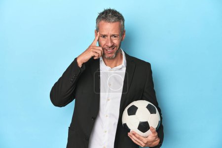Photo for Caucasian football coach, middle-aged on blue set showing a disappointment gesture with forefinger. - Royalty Free Image