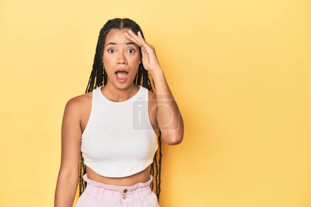 Photo for Young Indonesian woman on yellow studio backdrop shouts loud, keeps eyes opened and hands tense. - Royalty Free Image