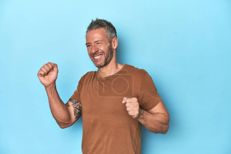 Photo for Middle-aged caucasian man on blue backdrop dancing and having fun. - Royalty Free Image