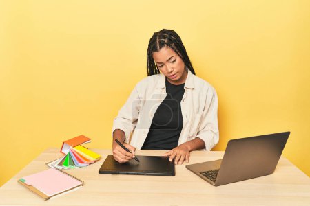 Téléchargez les photos : Jeune Indonésien en chemise rayée tenant un ordinateur portable sur un fond de studio jaune - en image libre de droit