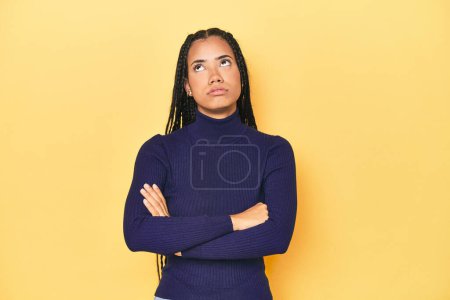 Photo for Young Indonesian woman on yellow studio backdrop tired of a repetitive task. - Royalty Free Image