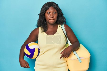 Photo for Young curvy woman with cooler and ball confused, feels doubtful and unsure. - Royalty Free Image