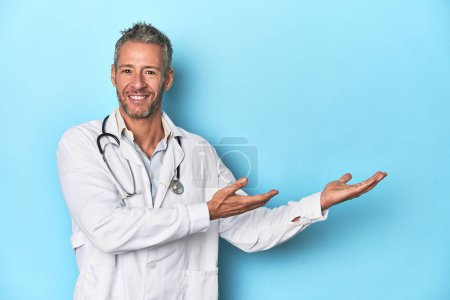 Foto de Caucásico de mediana edad médico masculino en un fondo de estudio azul - Imagen libre de derechos