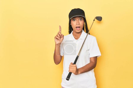 Photo for Indonesian female golfer on yellow backdrop having an idea, inspiration concept. - Royalty Free Image