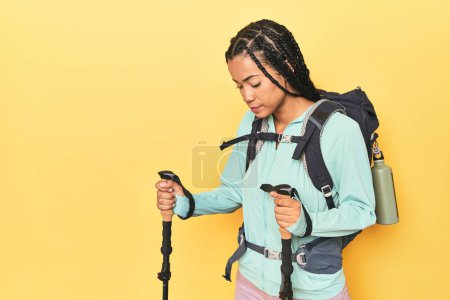 Photo for Indonesian hiker with backpack and poles on yellow - Royalty Free Image