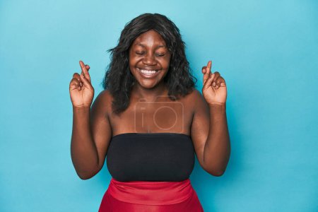 Téléchargez les photos : Jeune femme courbée afro-américaine croisant les doigts pour avoir de la chance - en image libre de droit