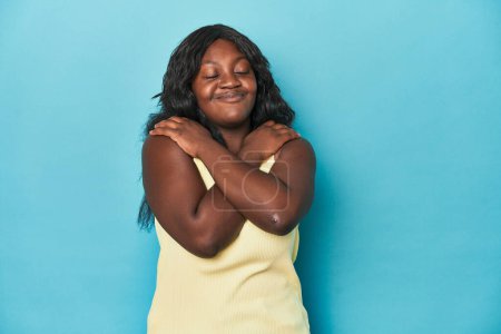 Foto de Joven africana americana mujer con curvas abrazos, sonriente despreocupado y feliz. - Imagen libre de derechos