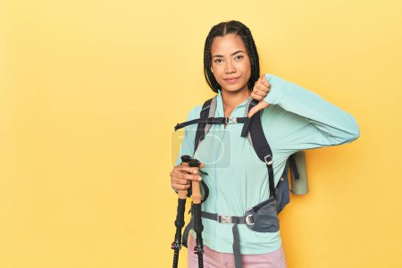 Téléchargez les photos : Femme indonésienne avec équipement de randonnée sur jaune montrant un geste détestable, pouces vers le bas. Concept de désaccord. - en image libre de droit