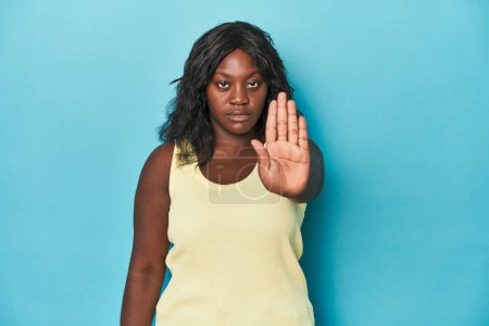 Téléchargez les photos : Jeune femme courbée afro-américaine debout avec la main tendue montrant le signe d'arrêt, vous empêchant. - en image libre de droit