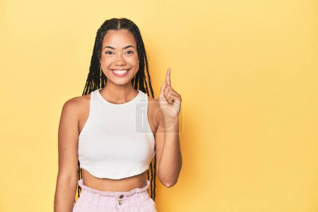 Téléchargez les photos : Jeune femme indonésienne sur fond de studio jaune montrant numéro un avec doigt. - en image libre de droit