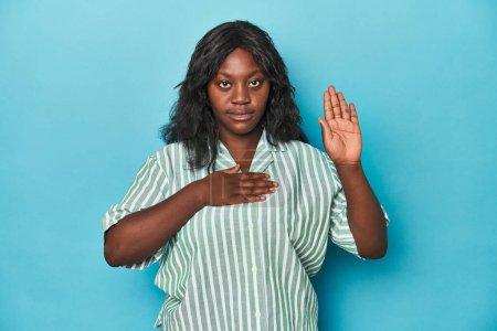 Foto de Joven africana americana curvilínea haciendo un juramento, poniendo la mano en el pecho. - Imagen libre de derechos