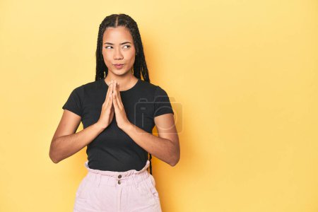 Téléchargez les photos : Jeune femme indonésienne sur fond de studio jaune faire plan à l'esprit, la mise en place d'une idée. - en image libre de droit