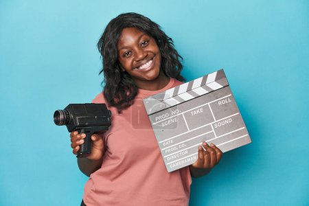 Photo for Creative curvy woman with film camera and clapperboard - Royalty Free Image