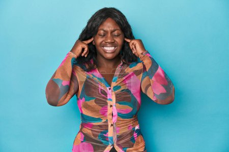 Téléchargez les photos : Jeune femme afro-américaine courbée couvrant les oreilles avec des doigts, stressée et désespérée par une ambiance bruyante. - en image libre de droit