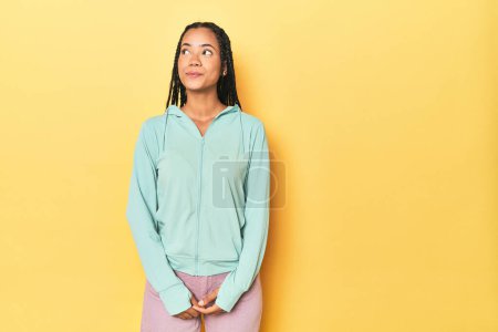 Photo for Indonesian sporty woman on yellow backdrop dreaming of achieving goals and purposes - Royalty Free Image