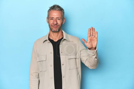 Photo for Middle-aged caucasian man on blue backdrop smiling cheerful showing number five with fingers. - Royalty Free Image