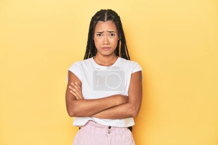Photo for Young Indonesian woman on yellow studio backdrop unhappy looking in camera with sarcastic expression. - Royalty Free Image
