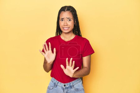 Photo for Young Indonesian woman on yellow studio backdrop rejecting someone showing a gesture of disgust. - Royalty Free Image