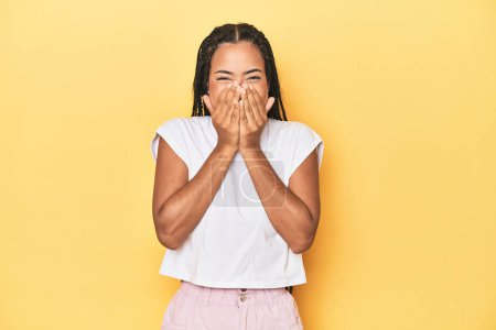 Photo for Young Indonesian woman on yellow studio backdrop laughing about something, covering mouth with hands. - Royalty Free Image