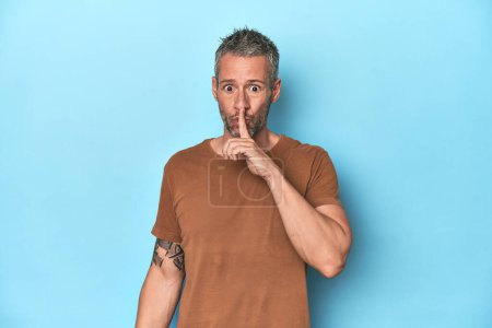 Photo for Middle-aged caucasian man on blue backdrop keeping a secret or asking for silence. - Royalty Free Image