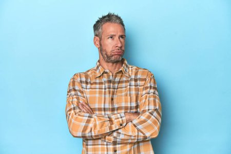 Photo for Middle-aged caucasian man on blue backdrop tired of a repetitive task. - Royalty Free Image