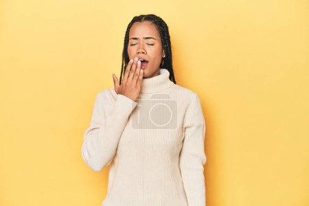 Téléchargez les photos : Jeune femme indonésienne sur fond de studio jaune bâillant montrant un geste fatigué couvrant la bouche avec la main. - en image libre de droit