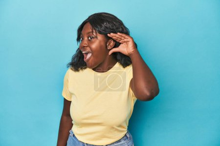 Foto de Joven africana americana curvilínea mujer tratando de escuchar un chisme. - Imagen libre de derechos
