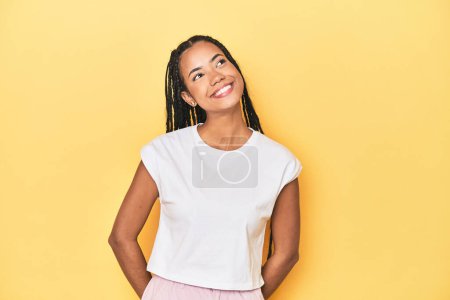Photo for Young Indonesian woman on yellow studio backdrop relaxed and happy laughing, neck stretched showing teeth. - Royalty Free Image