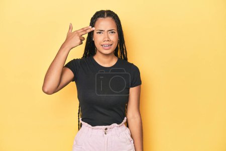 Téléchargez les photos : Jeune femme indonésienne sur fond de studio jaune montrant un geste de déception avec index. - en image libre de droit