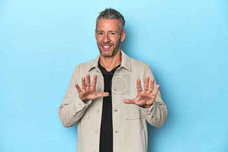 Photo for Middle-aged caucasian man on blue backdrop rejecting someone showing a gesture of disgust. - Royalty Free Image