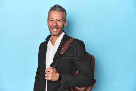 Téléchargez les photos : Homme d'affaires avec un sac à dos sur fond de studio bleu - en image libre de droit