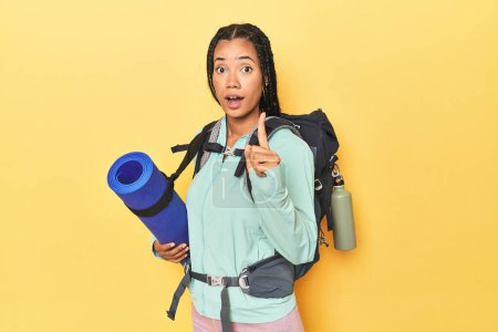 Photo for Indonesian woman ready for mountain trip on yellow having an idea, inspiration concept. - Royalty Free Image