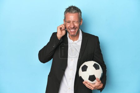 Foto de Entrenador de fútbol caucásico, de mediana edad en conjunto azul que cubre las orejas con las manos. - Imagen libre de derechos