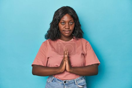 Photo for Young african american curvy woman praying, showing devotion, religious person looking for divine inspiration. - Royalty Free Image