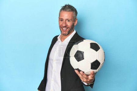 Photo for Football coach with soccer ball on blue studio backdrop - Royalty Free Image