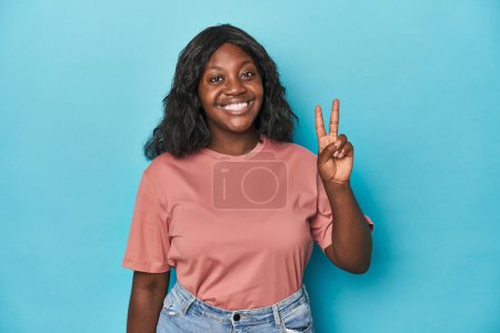 Foto de Joven africana americana curvilínea mujer alegre y despreocupada mostrando un símbolo de paz con los dedos. - Imagen libre de derechos