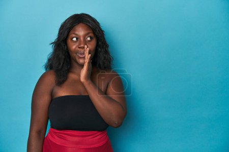Foto de Joven africana americana curvilínea mujer está diciendo un secreto caliente frenando noticias y mirando a un lado - Imagen libre de derechos