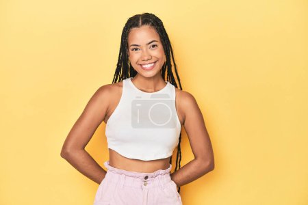 Photo for Young Indonesian woman on yellow studio backdrop happy, smiling and cheerful. - Royalty Free Image