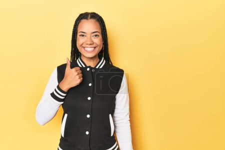 Photo for Indonesian woman in classic black baseball jacket smiling and raising thumb up - Royalty Free Image