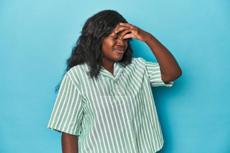 Foto de Joven afroamericana mujer con curvas que tiene un dolor de cabeza, tocando la parte delantera de la cara. - Imagen libre de derechos