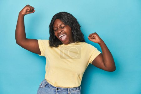 Foto de Joven afroamericana curvilínea mujer levantando puño después de una victoria, concepto ganador. - Imagen libre de derechos