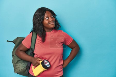 Photo for Curvy explorer with backpack and flashlight dreaming of achieving goals and purposes - Royalty Free Image