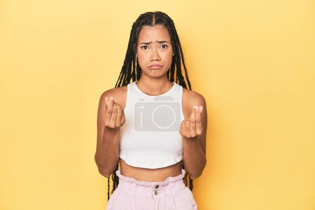 Photo for Young Indonesian woman on yellow studio backdrop showing that she has no money. - Royalty Free Image