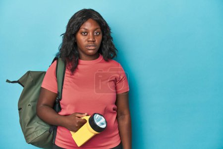 Photo for Ready for adventure, curvy woman with backpack on blue backdrop - Royalty Free Image