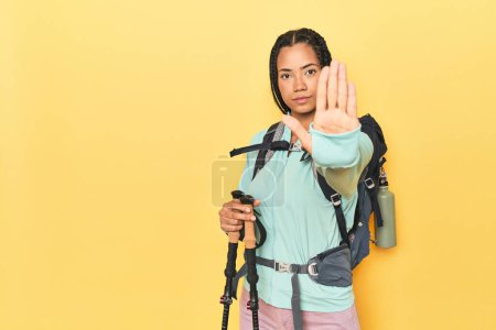 Foto de Mujer indonesia con equipo de senderismo en posición amarilla con la mano extendida mostrando señal de stop, lo que le impide. - Imagen libre de derechos