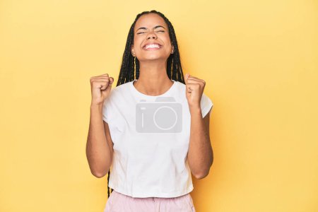 Photo for Young Indonesian woman on yellow studio backdrop celebrating a victory, passion and enthusiasm, happy expression. - Royalty Free Image